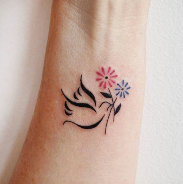 small dove tattoo with flower on wrist