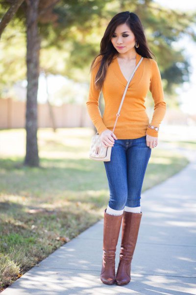 Custom-fit sweater with mustard and V-neckline, blue jeans and gray knee-high boots