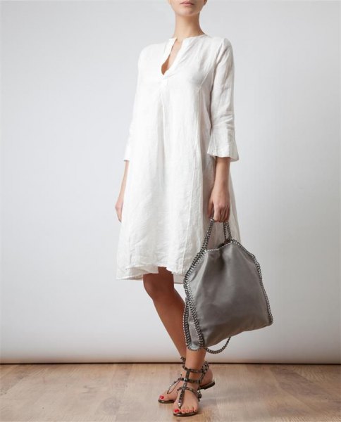 Knee-length dress made of white linen with bell sleeves and sandals