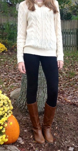 white cable knit sweater with black leggings and knee-high boots made of brown leather