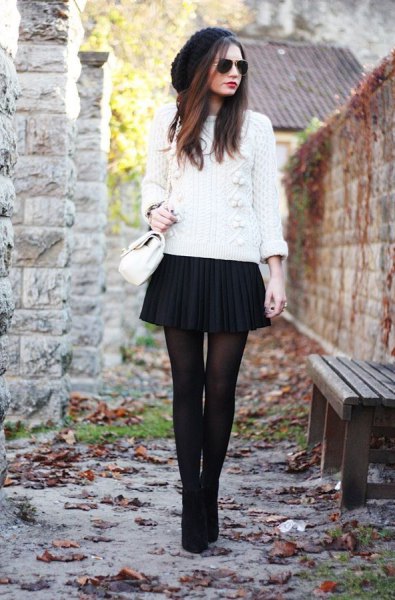 white cable knit sweater with black mini pleated skirt