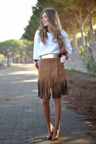 white cable knit sweater with metal belt and knee-length fringed skirt
