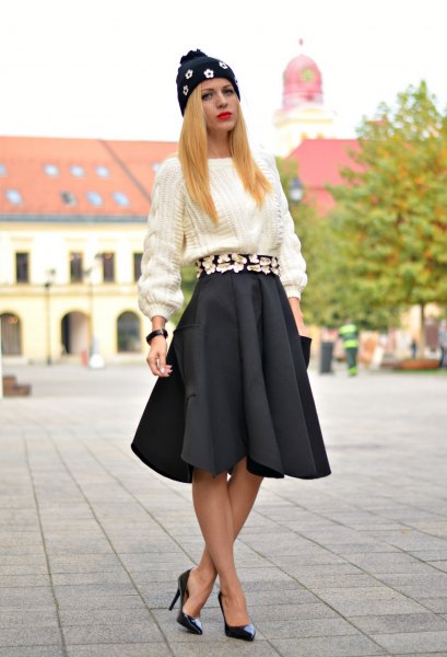 white, coarsely knitted sweater with black pleated skirt and heels