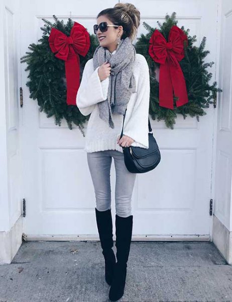 white, coarsely knitted sweater with gray skinny jeans and black, knee-high, high boots