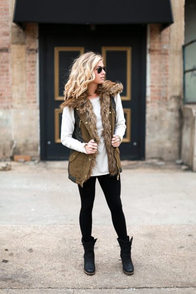 White crew neck sweater and olive green military vest made of faux fur