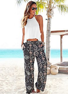 white, short halterneck top with black beach pants with tribal print