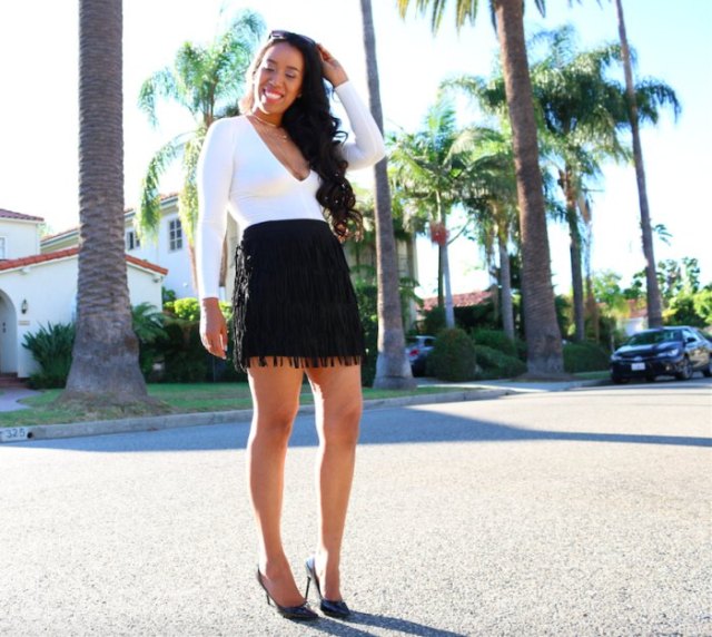 white, low-slung, long-sleeved top with V-neck and black mini skirt