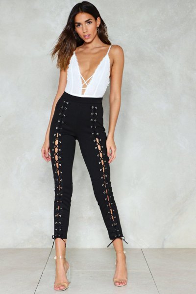white top with deep V-neckline and black, narrow lace-up trousers