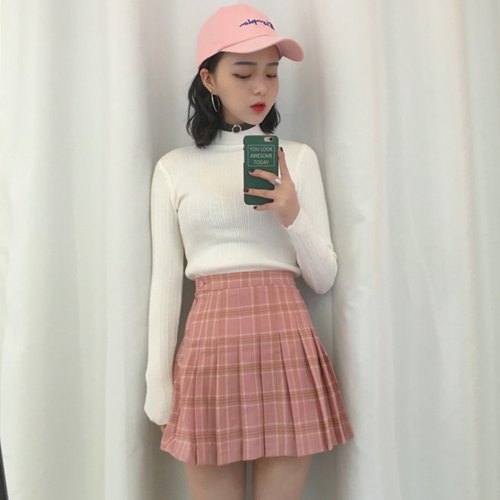 white mock-neck sweater with pink, high-waisted pleated mini skirt