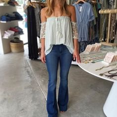 white blouse pleated off the shoulder with flared blue jeans