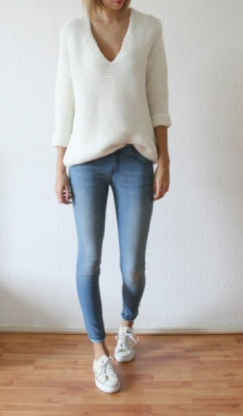 white knitted sweater with relaxed fit and V-neckline and light blue skinny jeans