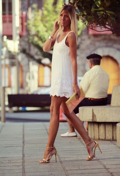 white lace dress with scalloped hem and golden high heels with open toes