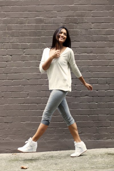 white sweater with scoop neckline and gray knee-length skinny jeans