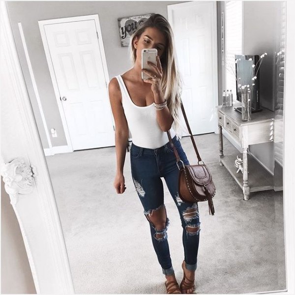 white tank top with scoop neckline and heavily ripped dark gray skinny jeans