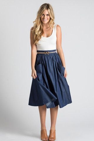 white tank top with scoop neckline and dark blue pleated midi skirt with belt and front pockets