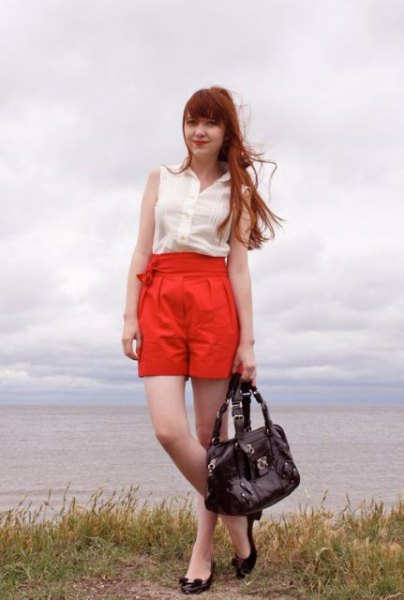 white sleeveless chiffon blouse with orange, pulled-up, pleated shorts
