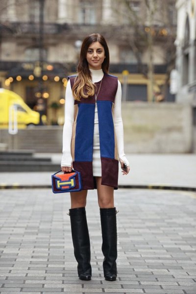 white sweater dress with sleeveless leather jacket in black and blue