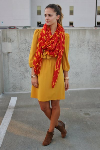 yellow mini dress with fit and flare with orange-gold scarf
