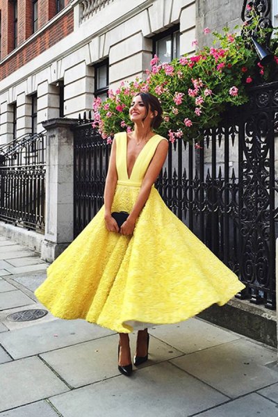 yellow lace fit and flare midi dress with deep V-neckline and black heels