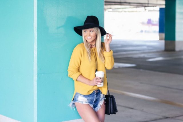 yellow sweater with blue mini-shorts made of ripped denim and floppy hat